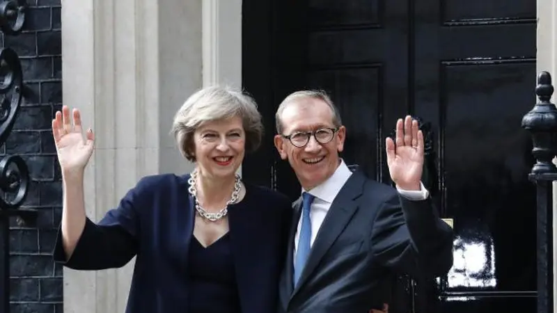 PM Theresa May dan sang suami, Philip melambaikan tangan di depan Downing Street 10