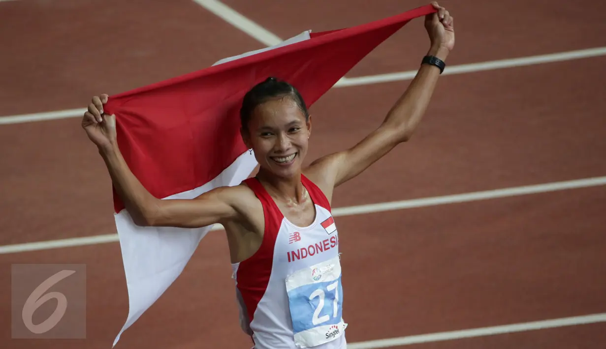 Atlet Indonesia, Rini Budiarti membentangkan bendera Merah Putih usai finish pertama lari halang rintang 3.000 meter SEA Games ke-28 di National Stadium, Singapura, (12/6/2015). Rini mencatat waktu 10 menit 20,40 detik. (Liputan6.com/Helmi Fithriansyah)