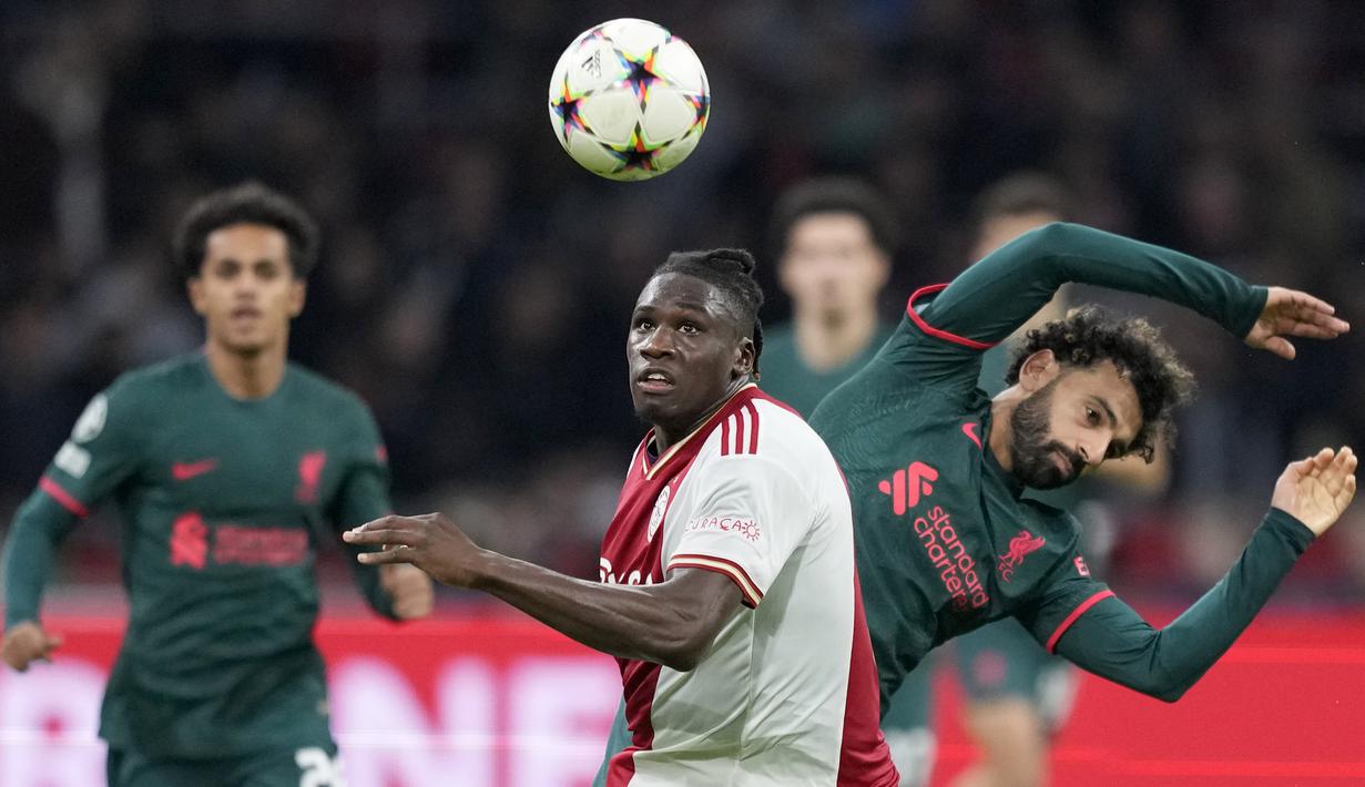 Bek Ajax Amsterdam Calvin Bassey berebut bola dengan penyerang Liverpool Mohamed Salah pada matchday kelima Grup A Liga Champions 2022-2023 di Johan Cruiff Arena,  Kamis (27/10/2022) dini hari WIB. Liverpool akhirnya ikut memastikan diri melaju ke babak 16 besar Liga Champions. (AP Photo/Peter Dejong)
