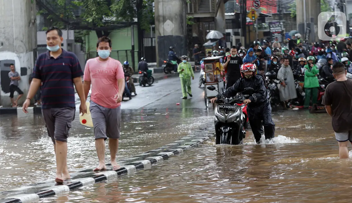 Pengendara mendorong sepeda motornya melewati banjir yang menggenangi kawasan Jalan Wolter Monginsidi Jakarta dan sekitarnya, Sabtu (20/2/2021). Hujan yang mengguyur Jakarta sejak Jumat (19/2) membuat sejumlah titik di Jakarta terendam banjir. (Liputan6.com/Helmi Fithriansyah)