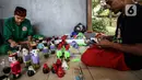Chairuddin (40) bersama rekannya menyelesaikan pembuatan ondel-ondel dari botol bekas di Sanggar Rumah Kreasi, Jakarta, Minggu (13/6/2021). Botol bekas dimanfaatkan menjadi ondel-ondel untuk dijual dengan harga sepasang Rp35 ribu dan bisa membuat ratusan setiap harinya. (Liputan6.com/Johan Tallo)