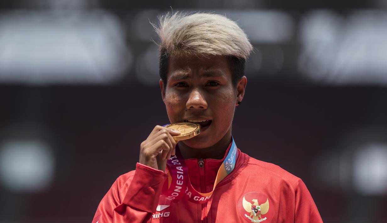 Atlet lompat jauh Indonesia, Rica Oktavia, melakukan selebrasi gigit medali usai meraih medali emas Asian Para Games 2018 di SUGBK, Jakarta, Senin (8/10/2018). (Bola.com/Vitalis Yogi Trisna)