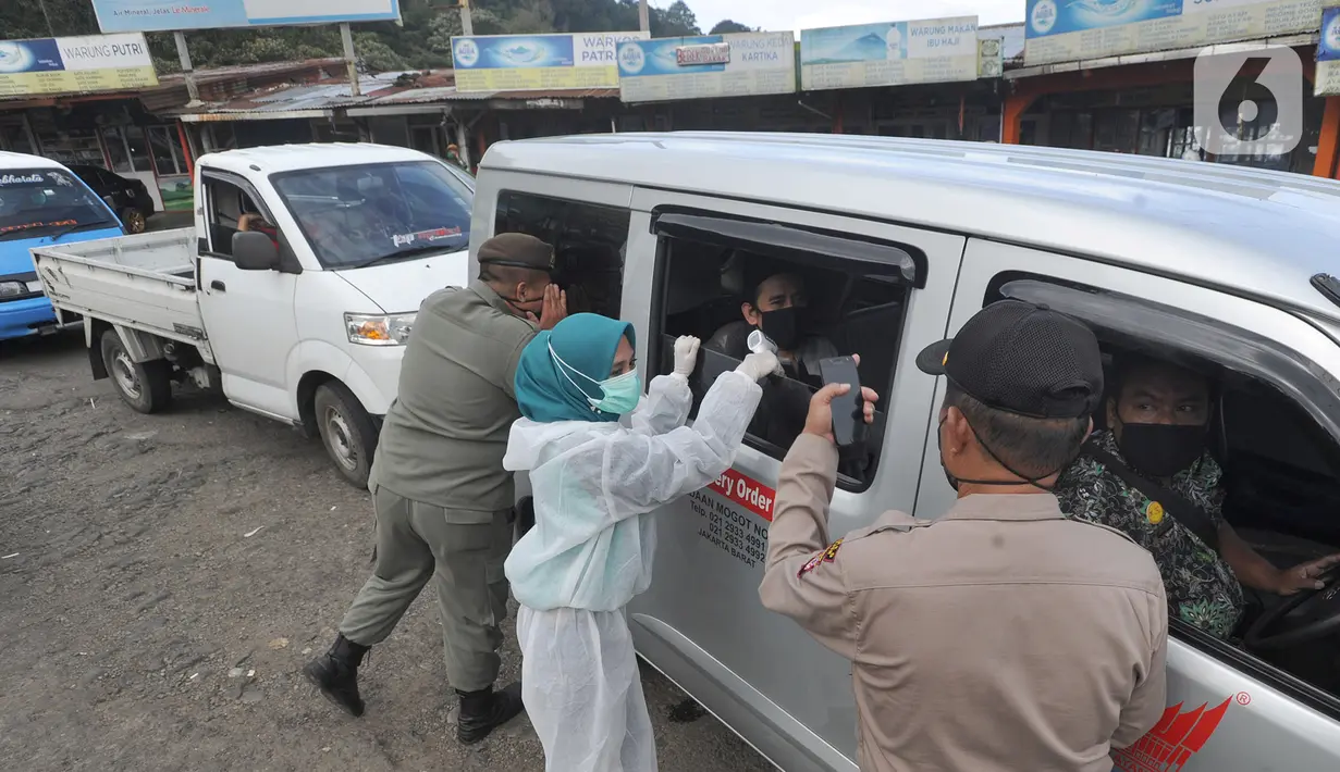 Petugas memeriksa surat keterangan lolos uji rapid test pada warga yang akan melakukan perjalanan di Pos Pam Puncak Pass, Cianjur, Minggu (17/5/2020). Mereka diperbolehkan melakukan perjalanan kecuali dilengkapi surat tugas atau  surat keterangan sehat dari pihak berwenang. (merdeka.com/Arie Basuki)