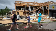 Orang-orang berjalan melewati bangunan yang rusak, beberapa jam setelah badai dahsyat menerjang aera di Le Cret-du-Locle dekat La Chaux-de-Fonds, Swiss barat, Senin (24/7/2023). (Fabrice COFFRINI / AFP)