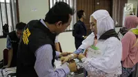 Panitia Penyelenggara Ibadah Haji (PPIH) memberikan gelang untuk calon jemaah haji kloter pertama di Asrama Haji, Jakarta, Sabtu (6/7/2019). Sebelum diberangkatkan, petugas mengecek kembali 385 calon jamaah untuk melakukan kelengkapan administrasi. (Liputan6.com/Faizal Fanani)