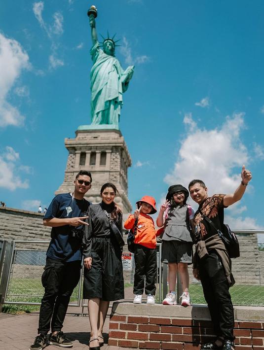 Anang Hermansyah dan Ashanty saat berpose bersama ketiga buah hatinya, Azriel, Arsy, Dan juga Arsya di bawah Patung Liberty.  Liburan kali ini, keluarga Ashanty-Anang Hermansyah tanpa kehadiran Aurel Hermansyah. Terasa ada yang kurang ya. (Instagram/ashanty_ash)