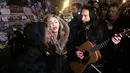 Penyanyi Madonna (tengah) bernyanyi di samping gitarisnya Monte Pittman (tengah kanan) dan anaknya David Banda (kiri) di place de la Republique di Paris untuk mengenang korban serangan teror 13 November di Paris, Kamis (10/12/2015). (JULES MAHE/AFP)