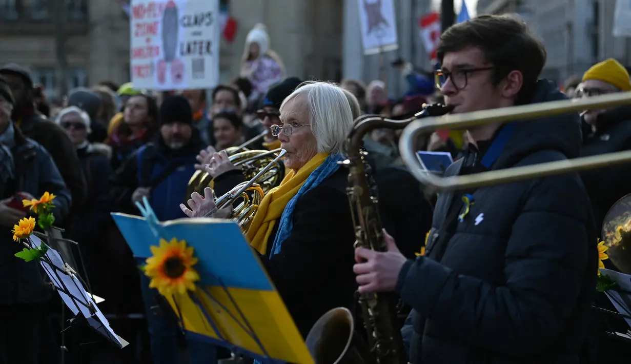 Puluhan musisi ambil bagian dalam pertunjukan flashmob "The Great Gate of Kyiv from pictures at an Exhibition" yang dipimpin seorang komposer Rusia-Inggris terkenal untuk menunjukkan dukungan terhadap Ukraina setelah invasi Rusia, di Trafalgar Square, London, Minggu (6/3/2022). (JUSTIN TALLIS/AFP)