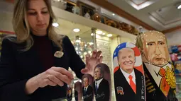 Penjaga toko manampilkan Matryoshka yang berkarakter Putin dan Trumph di Moskow, Rusia (16/1). Matryoshka adalah boneka kayu bertumpuk yang berasal dari Rusia. (AFP/Alexander Nemenov)