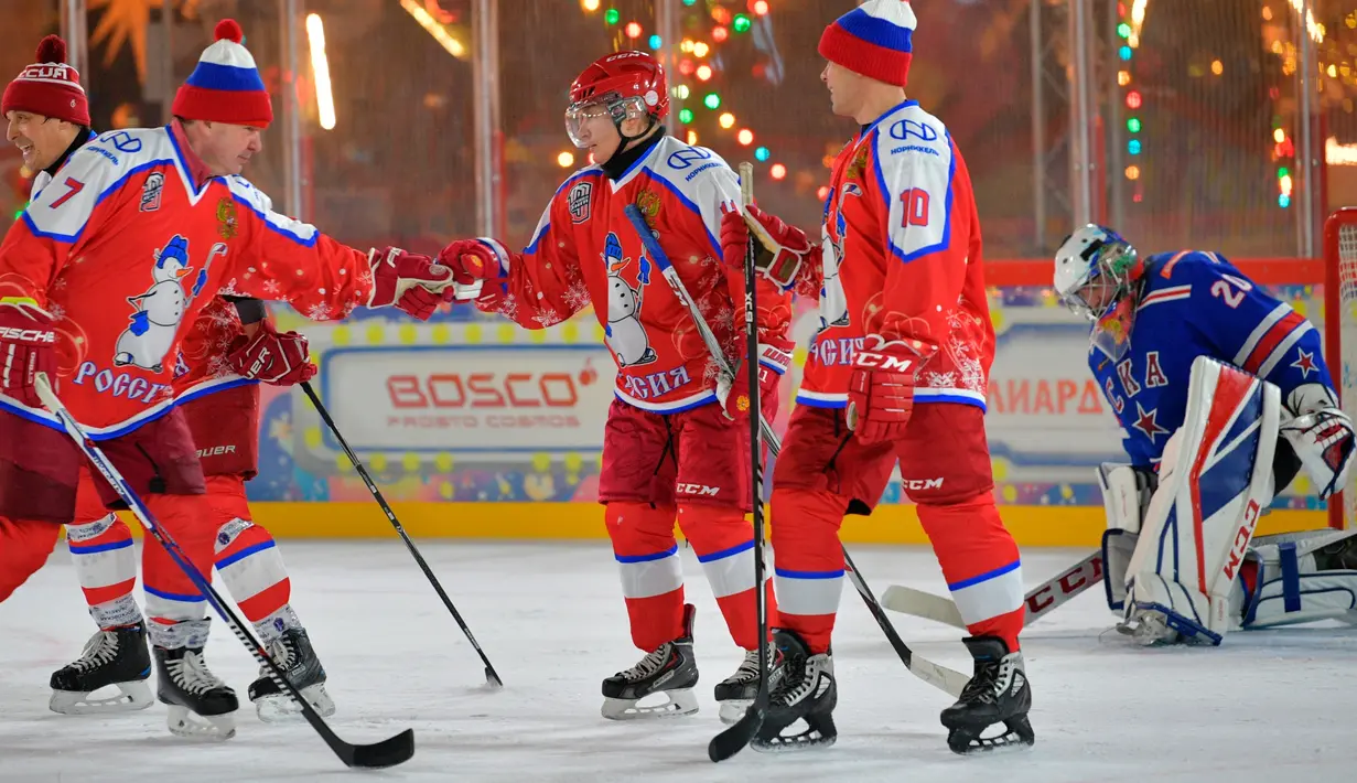 Presiden Rusia Vladimir Putin merayakan gol yang dicetaknya saat pertandingan eksihibisi Night Hockey League di gelanggang es di Lapangan Merah, Moskow, Rabu (25/12/2019). Night Hockey  merupakan turnamen berisi gabungan klub dan pemain amatir. (Mikhail Klimentyev, Sputnik, Kremlin Pool via AP)