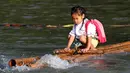 Seorang bocah memegang erat kayu di perahu rakit saat ingin menuju sekolah di sebuah desa terpencil di Montalban, Rizal, Filipina, Senin (13/6). Tidak adanya fasilitas jembatan membuat para siswa mempertaruhkan keselamatannya. (REUTERS/Erik De Castro)