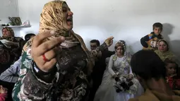 Seorang wanita menari saat pengantin wanita Heba (kanan) dan pengantin pria Ahmed (kiri) duduk di tengah perayaan pernikahan di Raqqa, Suriah (27/10). Kini ISIS sudah berhasil ditumpas dari Kota Raqqa. (AFP Photo/Delil Souleiman)