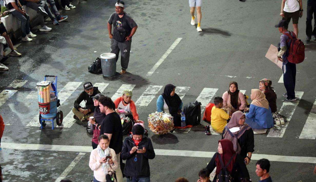 Ada delapan panggung yang tersebar di Jakarta dalam perayaan tahun baru 2026. Tampak dalam foto, beberapa pedagang asongan mencoba peruntungan saat malam pergantian tahun di kawasan Bundaran Hotel Indonesia, Jakarta, Rabu (31/12/2025). (Kapanlagi.com/Budy Santoso)
