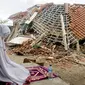 Seorang wanita berdoa di depan puing-puing bangunan di Lombok Barat, Nusa Tenggara Barat (NTB), Sabtu (11/8). BNPB menyatakan gempa Lombok hingga saat ini telah menewaskan 387 orang. (AP Photo/ Firdia Lisnawati)