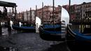 Perahu Gondola bersandar di laguna Venesia, Italia (29/12). Surutnya kanal ini mengakibatkan Gondola sulit berjalan dan banyak bersandar di pinggir Grand Canal di laguna Venesia, Italia. (REUTERS/Manuel Silvestri)