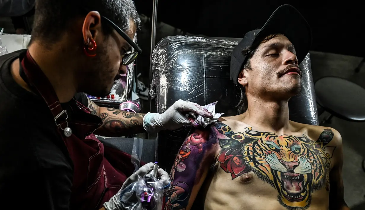 Seniman membuat tato di tangan seorang pria saat acara Expotattoo Colombia 2019 di Medellin, departemen Antioquia (2/6/2019). Para penggila tato antusias untuk mentato tubuhnya di festival tato terbesar di negara tersebut. (AFP Photo/Joaquim Sarmiento)