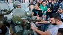 Para pengunjuk rasa mencoba membebaskan rekannya yang ditahan oleh polisi anti huru hara saat demonstrasi di luar kedutaan AS di Santiago, Chili (14/4). Mereka melakukan aksi menentang serangan AS ke Suriah. (AP / Esteban Felix)