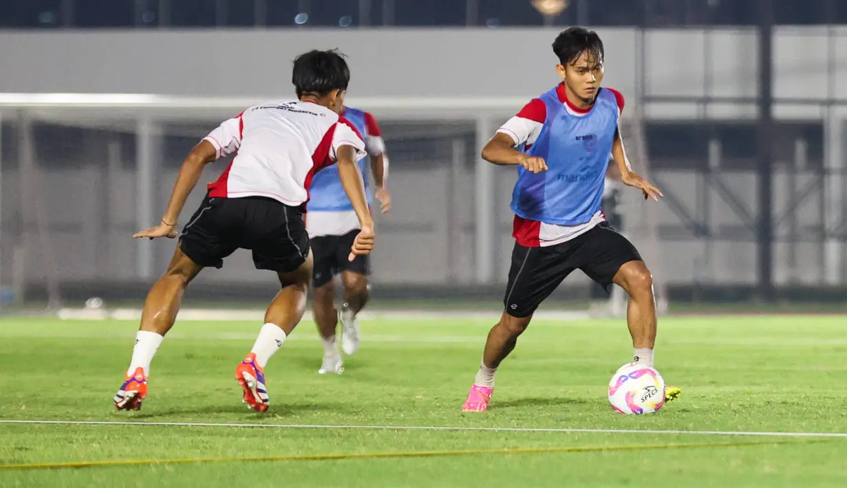 Aksi Riski Afrisal mencoba melewati rekannya dalam latihan Timnas Indonesia U-20 di Stadion Madya, Jakarta Pusat, pada Minggu (22/9/2024) malam WIB. (Bola.com/Abdul Aziz)