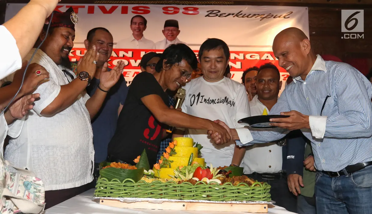Aktivis 98 Adian Napitupulu memberikan potongan tumpeng saat menggelar diskusi sekaligus syukuran kemenangan capres-cawapres nomor urut 01 Joko Widodo atau Jokowi dan Ma'ruf Amin versi quick count di Jakarta, Minggu (21/4). Diskusi bertajuk 'Setelah Menang Mau Apa?'. (Liputan6.com/JohanTallo)