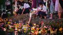 Orang-orang melepaskan lampion mengambang di kolam selama festival Loy Krathong di Bangkok (8/11/2022). Penghormatan tersebut dilakukan dengan cara melepaskan teratai yang dihiasi dengan lilin, dupa dan bunga ke air. (AFP/Lillian Suwanrumpha)