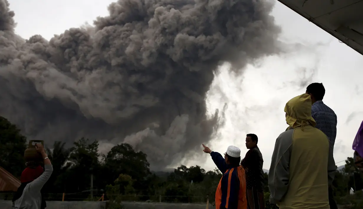 Sejumlah warga berkumpul melihat Gunung Sinabung yang tengah melontarkan awan panas di Desa Tiga Serangkai, Karo, Sumatera Utara, Rabu (24/6/2015). (REUTERS/Beawiharta)
