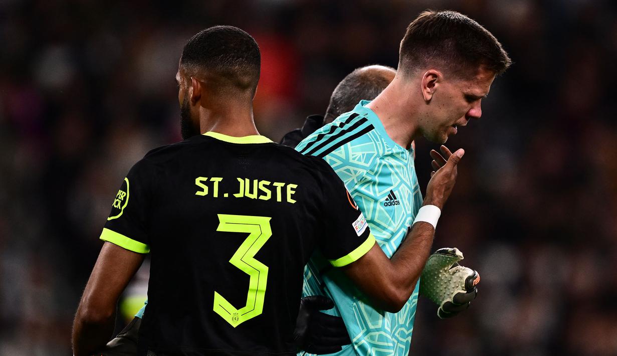 Kiper Juventus, Wojciech Szczesny berjalan meninggalkan lapangan dibantu oleh tim medis setelah mengalami sakit dada ketika pertandingan leg pertama perempat final Liga Europa 2022/2023 melawan Sporting CP di Allianz Stadium, Turin, Jumat (14/04/2023). Szczesny diketahui terkena paltisipasi jantung atau kondisi di mana seseorang merasakan kerja jantung yang kuat, cepat, atau tidak teratur. (AFP/Marco Bertorello)