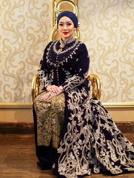 Reza Artamevia tampil luar biasa menawan dibalut kebaya beludru modern berwarna biru tua. Kebaya panjang ini memiliki bordir floral dari benang emas yang menambah kesan mewah dan mahal pada keseluruhan penampilan Reza Artamevia di sini, belum lagi padu padan kain batik kuning sebagai rok dan turban biru tua yang serasi. [Foto: Instagram/rezaartameviaofficial]