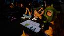 Seorang wanita bertopeng dengan pengunjuk rasa lainnya memblokir jalan ketika mereka menggelar protes terkait kebakaran hutan Amazon di luar Kedutaan Besar Brasil di Nicosia, Siprus, Jumat (23/8/2019). (AP Photo/Petros Karadjias)