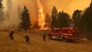Petugas pemadam kebakaran berusaha memadamkan apidi dekat Mariposa, California (23/7/2022). Api yang bergerak cepat membakar di luar Taman Nasional Yosemite telah memaksa evakuasi, menghanguskan lebih dari 11.500 hektar dan telah menghancurkan beberapa rumah sejak mulai Jumat sore. (Justin Sullivan/Getty Images/AFP)