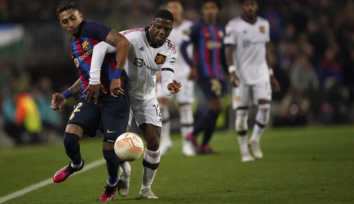 Bek (MU) Manchester United Tyrell Malacia berebut bola dengan penyerang Barcelona Raphinha pada leg pertama play-off babak gugur Liga Europa 2022/2023 di Camp Nou, Jumat (17/2/2023) WIB.  MU harus puas menutup laga kontra Barcelona dengan skor 2-2. (AP Photo/Joan Mateu Parra)