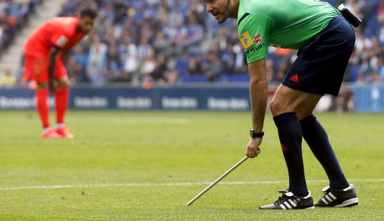 Wasit Antonio Mateu mengambil tongkat yang dilemparkan ke dalam stadion (REUTERS/Gustau Nacarino).