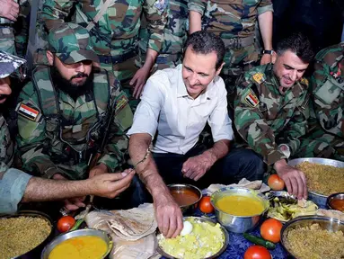 Presiden Suriah Bashar al-Assad dan pasukan setianya melahap hidangan buka puasa di Desa Marj al-Sultan, timur Ghouta, Damaskus, Suriah, Minggu (26/6). (REUTERS/Sana)