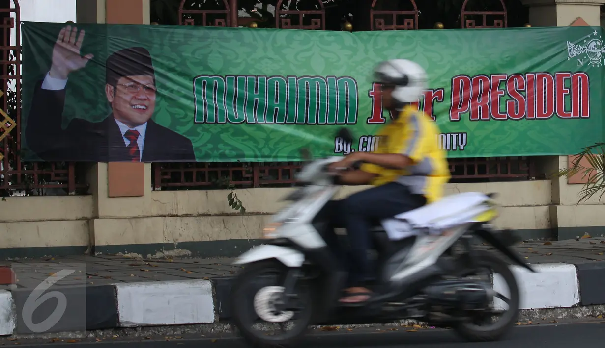 Pengendara motor melintasi spanduk bertuliskan 'Muhaimin for President' di pagar Masjid Sunda Kelapa, Jakarta, Sabtu (12/9). Pemasangan spanduk itu melanggar UU tentang larangan penggunaan tempat ibadah sebagai tempat kampanye. (Liputan6.com/Angga Yuniar)