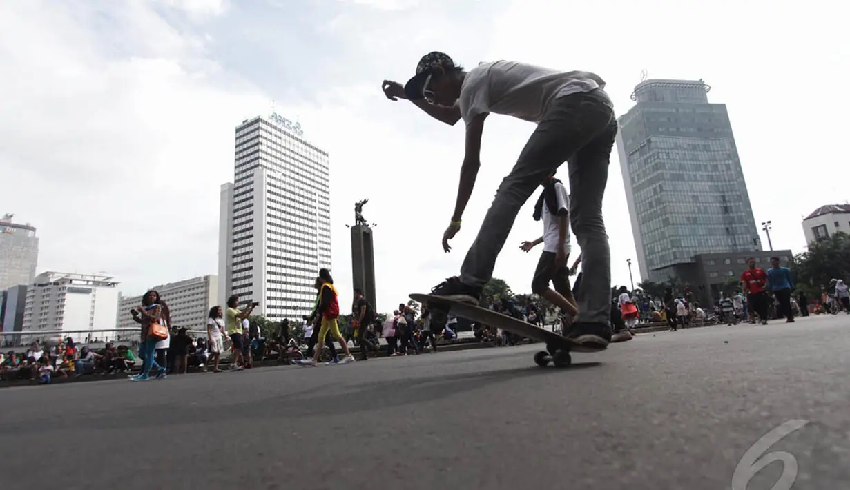 Aksi seorang remaja bermain skateboard di kawasan Bundaran HI Jakarta, Minggu (14/12/2015). (Liputan6.com/Faizal Fanani)
