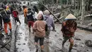 Tercatat, ada dua desa yang mengalami kerusakan parah, menjadi gelap gulita akibat abu vulkanik tebal, dan sebagian wilayahnya luluh lantak diterjang awan panas, yakni Desa Supiturang dan Dusun Kamar Kajang di Lumajang, Jawa Timur. Tampak dalam foto, orang-orang berjalan di tanah yang tertutup abu vulkanik setelah aliran piroklastik selama letusan Gunung Semeru di Desa Supiturang, Lumajang, Jawa Timur pada Kamis 20 November 2025. (Agus Harianto/AFP)