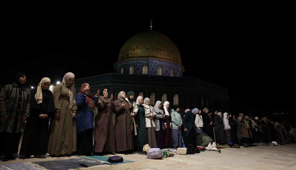 Jamaah memenuhi area terbuka di dekat Kubah Batu (Dome of the Rock) serta ruang salat utama lainnya untuk menandai dimulainya bulan suci Ramadan yang jatuh pada Rabu 18 Februari 2026. Tampa dalam foto, para wanita Palestina melaksanakan salat Tarawih pada malam pertama bulan suci Ramadan di dekat Kubah Batu, kompleks Masjid Al-Aqsa, Kota Tua Yerusalem pada 17 Februari 2026. (AHMAD GHARABLI/AFP)