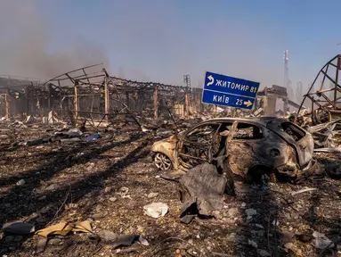 Pemandangan sebuah mobil yang hancur di tengah bangunan-bangunan yang rusak, serta rambu jalan yang menunjukkan arah dan jarak ke Kyiv dan Zhytomyr, setelah serangan Rusia menghantam sebuah gudang yang kemudian disusul oleh ledakan di desa Myla, wilayah Kyiv, Ukraina, Sabtu, 29 Agustus 2026. (Foto AP/Dan Bashakov)