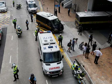 Polisi bersenjata lengkap menjaga mobil yang membawa mantan bankir Inggris, Rurik Jutting memasuki Pengadilan Tinggi di Hong Kong, Tiongkok, Selasa (25/10). Rurik didakwa atas pembunuhan dua warga negara Indonesia (WNI) di Hong Kong. (Reuters/Bobby Yip)