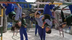 Seorang anak Tibet di pengasingan menggigit apel saat tergantung terbalik dari jeruji besi saat istirahat di Sekolah Hari Desa Anak-anak Tibet di Dharmsala, India (24/3/2022). Kehidupan sekolah perlahan kembali normal setelah sempat terganggu akibat pandemi COVID-19. (AP Photo/Ashwini Bhatia)