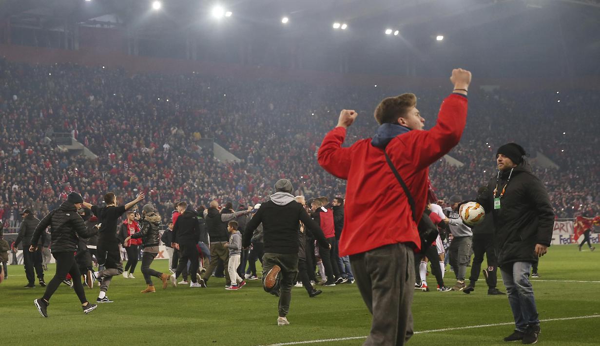 Para suporter Olympiakos turun ke lapangan merayakan kemenangan atas AC Milan pada laga Europa di Stadion Georgios Karaiskakis, Athena, Kamis (13/12). Olympiakos menang 3-1 atas AC Milan. (AP/Thanassis Stavrakis)