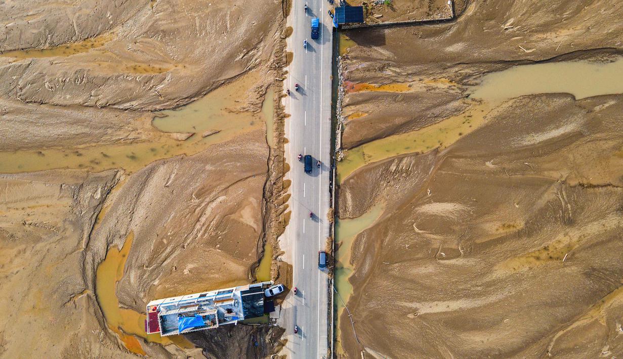 Kabupaten Pidie Jaya, termasuk kecamatan Meureudu, dikenal karena produktivitas padinya yang tinggi dan bahkan telah menerima penghargaan dari Kementerian Pertanian. Pada tahun-tahun sebelumnya, hasil panen rata-rata dilaporkan mencapai sekitar 8,5 ton per hektare. Tampak foto udara menunjukkan para komuter yang berkendara melewati sawah yang terendam lumpur setelah banjir bandang di Meureudu, Kabupaten Pidie Jaya, Provinsi Aceh, pada Senin 8 Desember 2025. (Chaideer MAHYUDDIN/AFP)