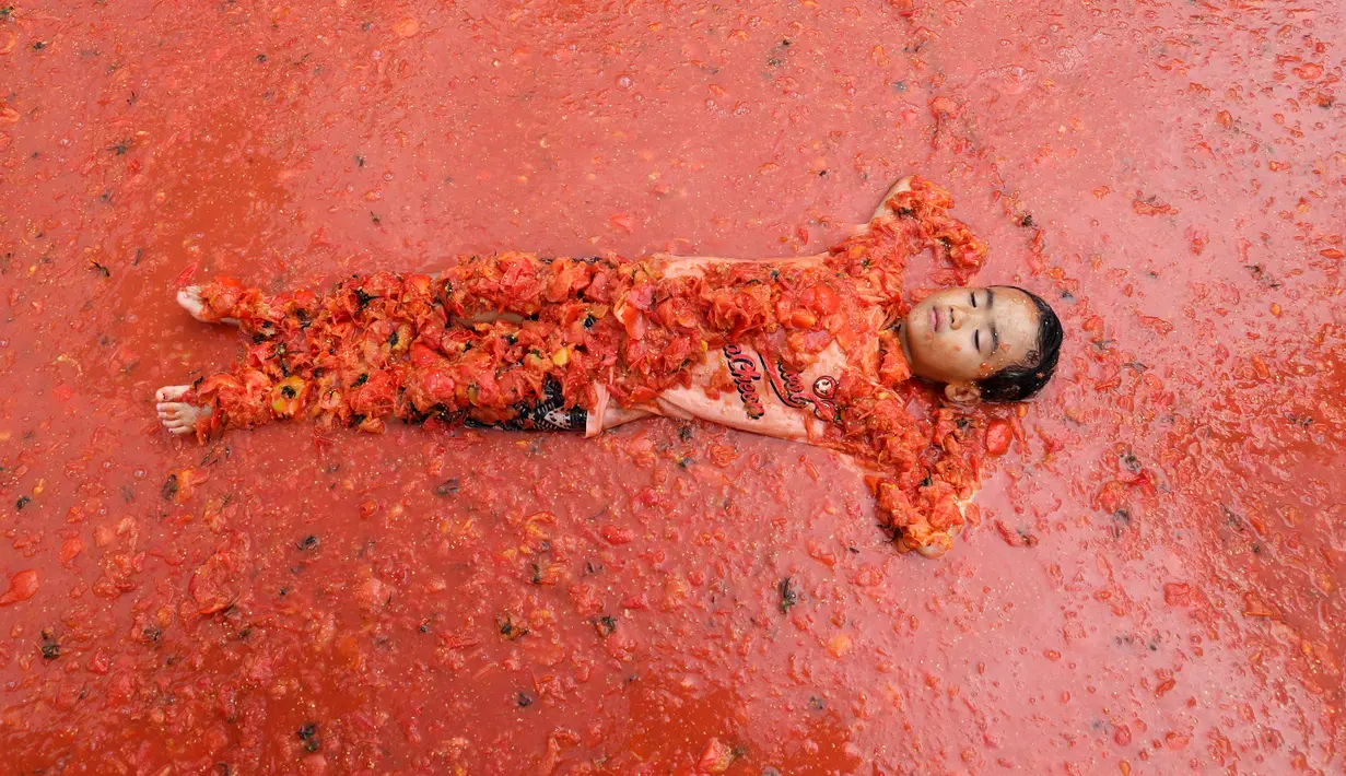 Seorang anak laki-laki berbaring di dalam kolam berisi tomat selama Festival Tomat di Hwacheon, Korea Selatan, 5 Agustus 2017. Festival untuk merayakan panen tomat ini berlangsung dari 4 - 7 Agustus. (AP Photo/Ahn Young-joon)