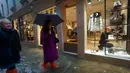 Pegawai toko merapikan sepatu saat warga berjalan di jalanan yang banjir akibat gelombang pasang yang menerjang Venesia, Italia, Selasa (12/11/2019). Venesia dilanda banjir akibat gelombang pasang setinggi 127 cm. (AP Photo/Luca Bruno)