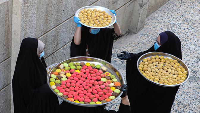 Sejumlah perempuan membawa kue untuk perayaan Idul Fitri yang akan datang di Basra, Irak, Jumat (22/5/2020). Idul Fitri menandai berakhirnya bulan suci Ramadan. (AP Photo/Nabil al-Jurani)