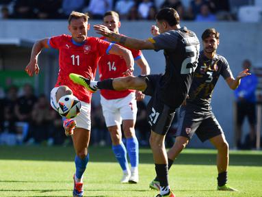 Penyerang Republik Ceko #11 Jan Kuchta dan gelandang Makedonia Utara #21 Jani Atanasov bersaing memperebutkan bola dalam laga uji coba terakhir jelang EURO 2024 di Malsovicka Arena, Hradec Kralove, Senin (10/6/2024) malam WIB. (Michal Cizek / AFP)