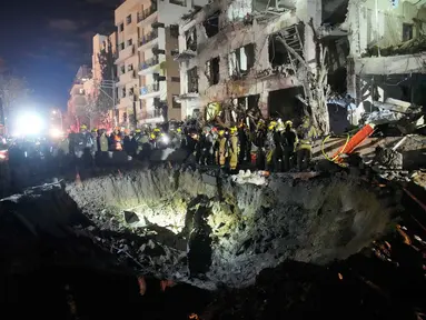 Para petugas dari Komando Pertahanan Dalam Negeri Israel memeriksa reruntuhan gedung apartemen yang rusak akibat serangan rudal Iran, di Tel Aviv, Israel, Minggu 1 Maret 2026 pagi waktu setempat. (AP Photo/Ohad Zwigenberg)