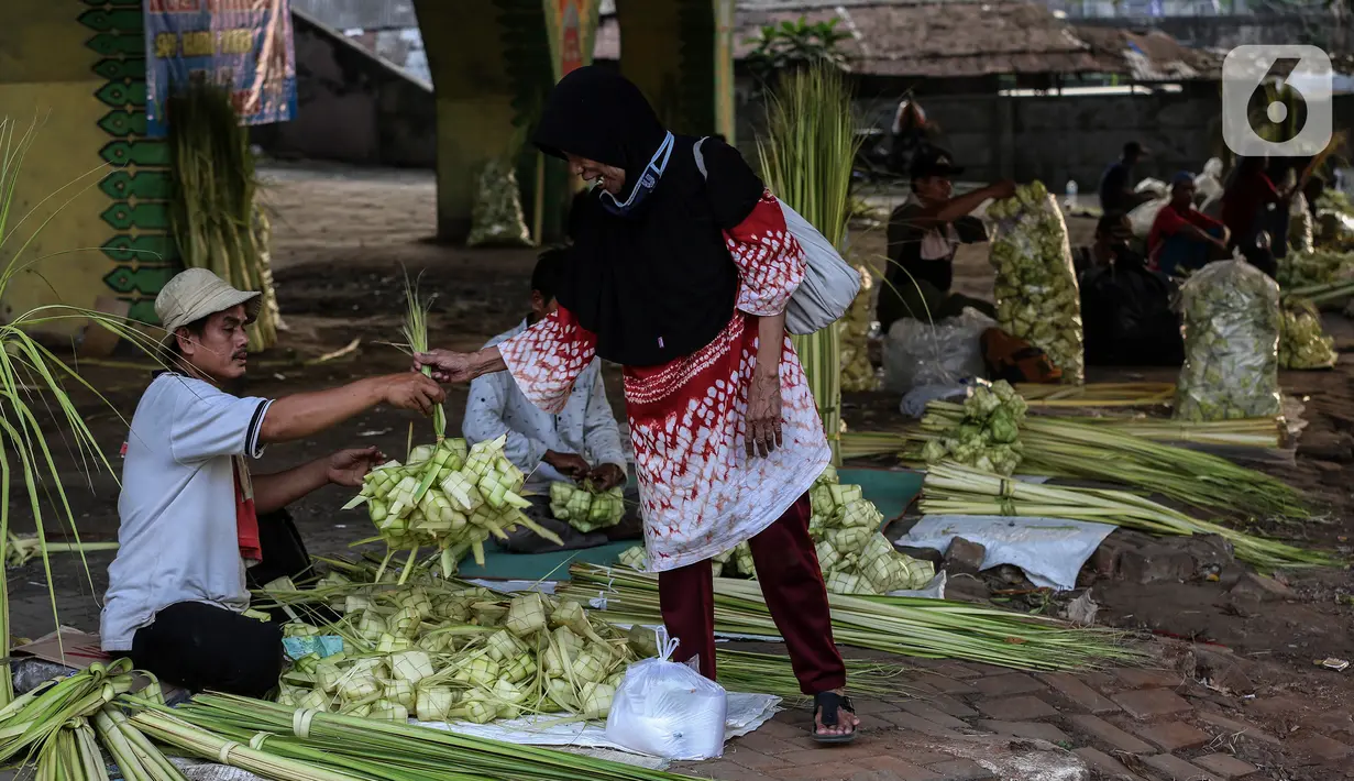 Pedagang musiman melayani pembeli kulit ketupat di bawah kolong jembatan kawasan Pesanggrahan, Jakarta, Jumat (8/7/2022). Pedagang musiman memanfaatkan Idul Adha untuk berjualan kulit ketupat. (Liputan6.com/Johan Tallo)