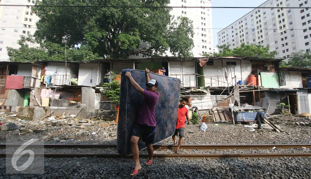 Warga membawa kasur saat alat berat merobohkan bangunan rumah mereka di kawasam Rawajati, Jakarta, Kamis (1/9). Penertiban tersebut menyebabkan warga terpaksa menyelamatkan barang berharga mereka ke tepi rel kereta api. (Liputan6.com/Immanuel Antonius)