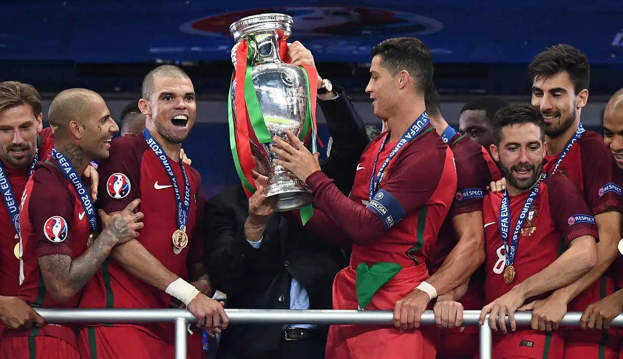 Pemain Timnas Portugal, Cristiano Ronaldo dan Pepe menerima trofi Piala Euro setelah mengalahkan Prancis di final Piala Euro 2016 yang berlangsung di Stade de France, Paris, (10/7/2016). (AFP/Franck Fife)