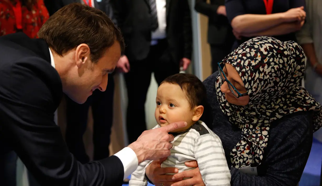 Presiden Prancis Emmanuel Macron menghibur seorang anak saat mengunjungi Graffiti's- Association Le Moulin Vert di Normandia, Prancis (5/4). Pada kunjungannya Presiden Emmanuel Macron berinteraksi dengan anak-anak autis. (AP / Christophe Ena, Pool)
